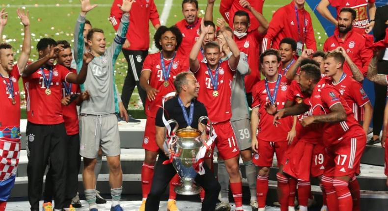 Bayern Munich players and coach Hansi Flick celebrate with the trophy after beating PSG in Sunday's Champions League final in Lisbon