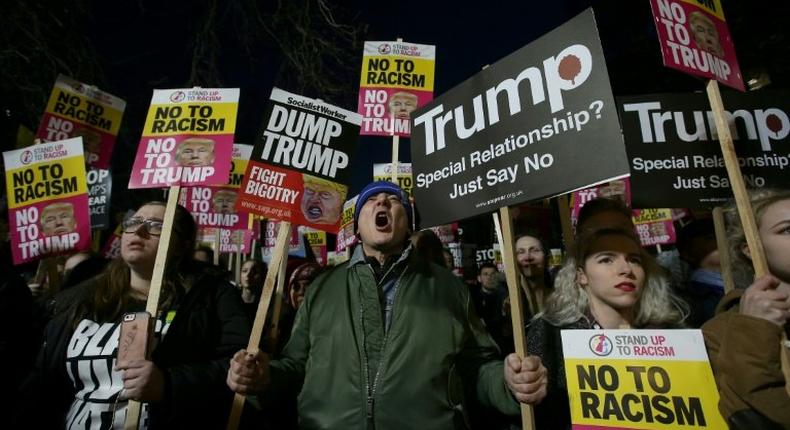 Demonstrators hold placards as they protest outside the US Embassy in London on January 20, 2017