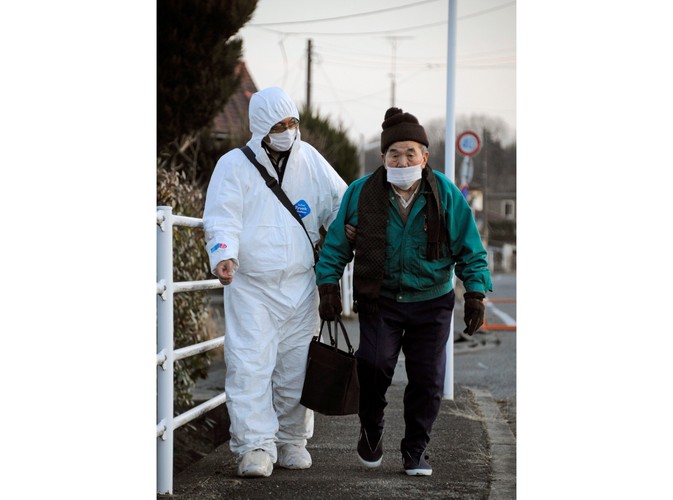 Starszy mężczyzna, odprowadzany do tymczasowego schroniska, w pobliżu elektrowni Daiichi w mieście Futaba w prefekturze Fukushima