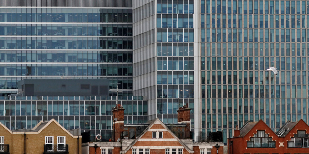 Apartment buildings are backdropped by skyscrapers of banks at Canary Wharf in London, Britain October 30, 2015.
