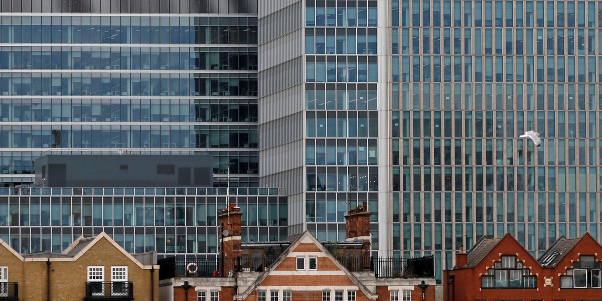 Apartment buildings are backdropped by skyscrapers of banks at Canary Wharf in London, Britain October 30, 2015.