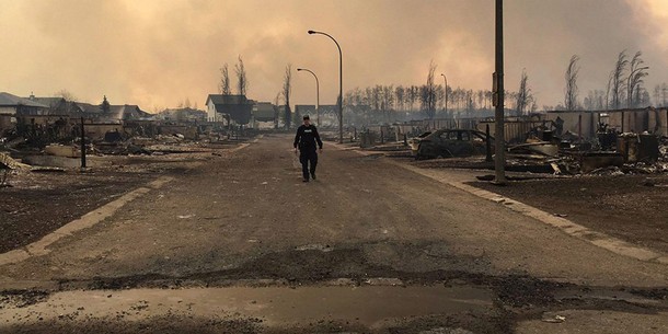 A Mountie surveys the damage on a street in Fort McMurray Alberta