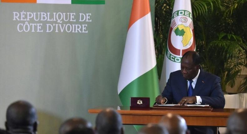 Ivory Coast's president Alassane Ouattara signs the country's revisited constitution on November 8, 2016 at the presidential palace in Abidjan