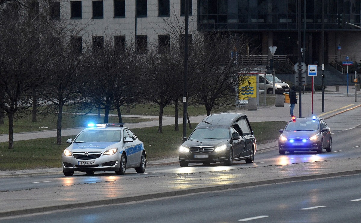 Karawan z ekshumowanym ciałem, w asyście wozów policyjnych wyjeżdża z Powązek Wojskowych