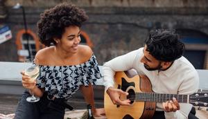 Man holding an acoustic guitar beside a woman [Photo: Viktoria Slowikowska]