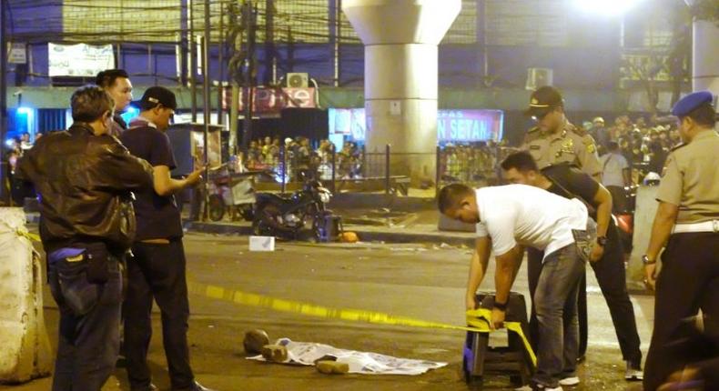 Police officers and investigators work at the scene of a bomb blast that killed at least one person near a bus terminal in Jakarta, on May 24, 2017