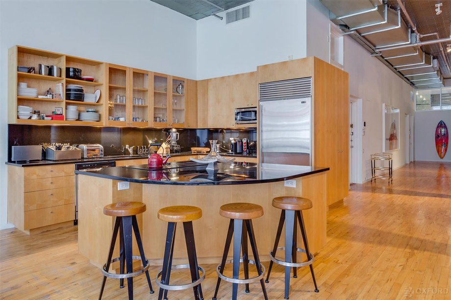 The open kitchen with black granite countertops has a functional island and bar stool seating.