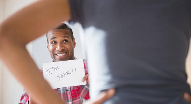 Man showing 'I'm Sorry' sign to angry girlfriend