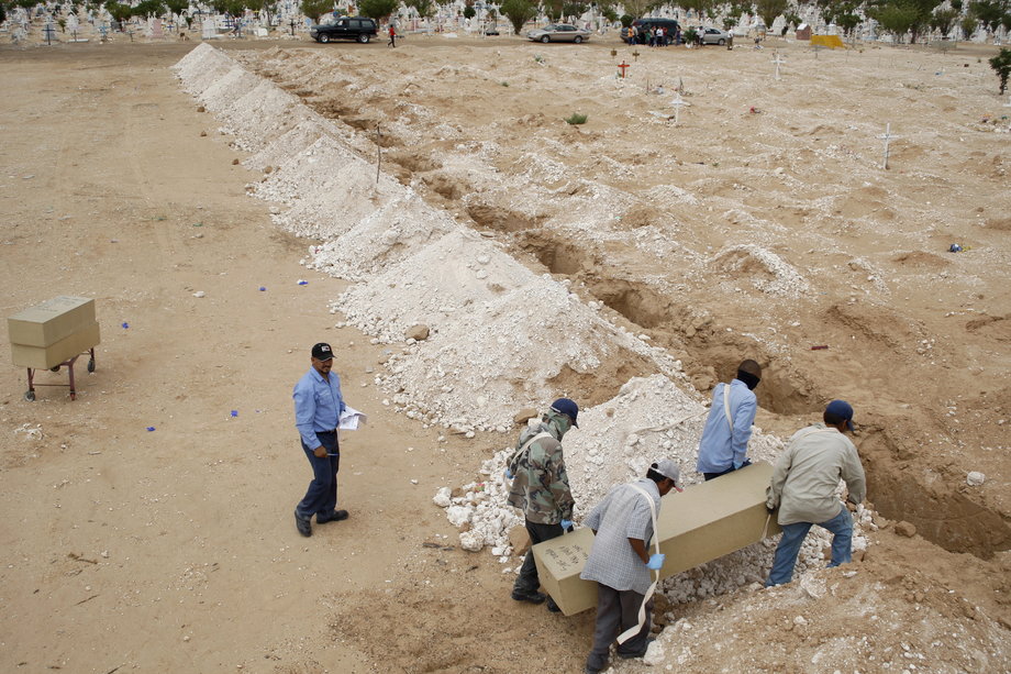Morgue workers carry a coffin containing an unidentified body toward a grave at San Rafael cemetery on the outskirts of Ciudad Juarez, August 13, 2012.