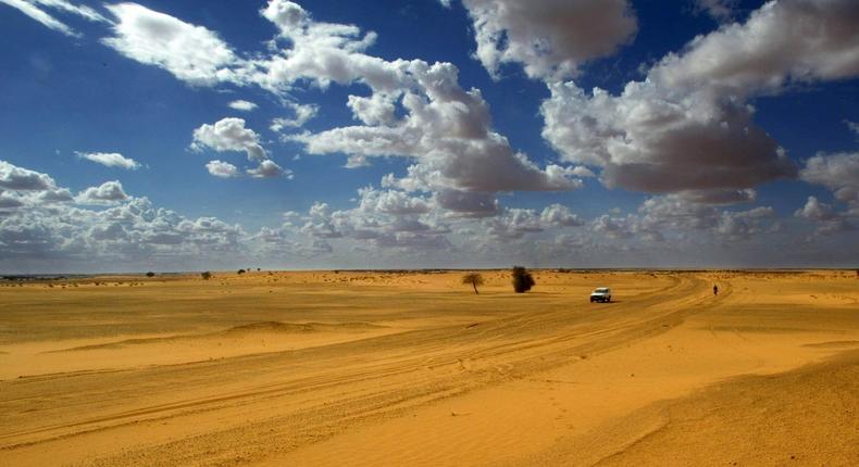 A vehicle passes along the border of the Sahara desert