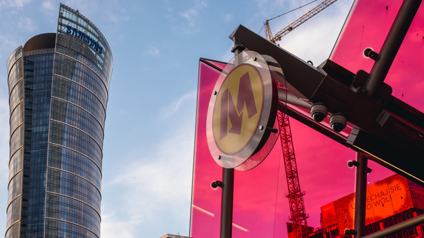 Symbol warszawskiego metra na stacji Rondo Daszyńskiego, w tle budynek Warsaw Spire