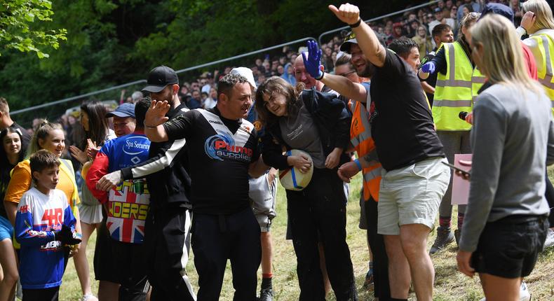 The winner of the first Cooper's hill women's downhill race smiles with her cheese and supporters after being knocked unconscious during the race on May 29, 2023 in Gloucester, United Kingdom.Annabel Lee-Ellis/Getty Images