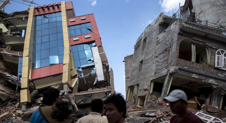 People walk past a collapsed building after a fresh 7.3 earthquake struck, in Kathmandu, Nepal, May 12, 2015.     REUTERS/Athit Perawongmetha