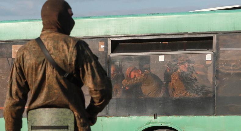 A service member of pro-Russian troops stands guard on a road near a bus carrying Ukrainian soldiers, who surrendered at the besieged Azovstal steel mill in the course of Ukraine-Russia conflict, near Mariupol, Ukraine May 20, 2022.