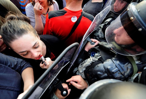 A girl puts lipstick and kisses the shield of the police in front of the Macedonian government build