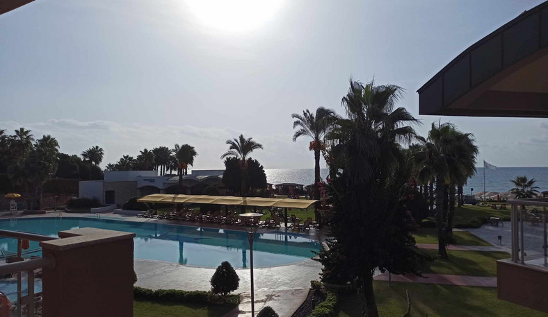 Krajobrazy przy wyjściu z hotelu. Słońce, baseny i palmy, a w tle morze