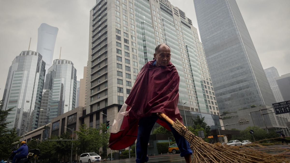 Pracownik zamiata ulicę w Centralnej Dzielnicy Biznesowej w deszczowy dzień w Pekinie