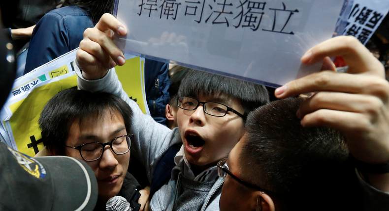 Student leader Joshua Wong with a sign saying defend judicial independence during a confrontation with security guards at a news conference held by Carrie Lam in Hong Kong.