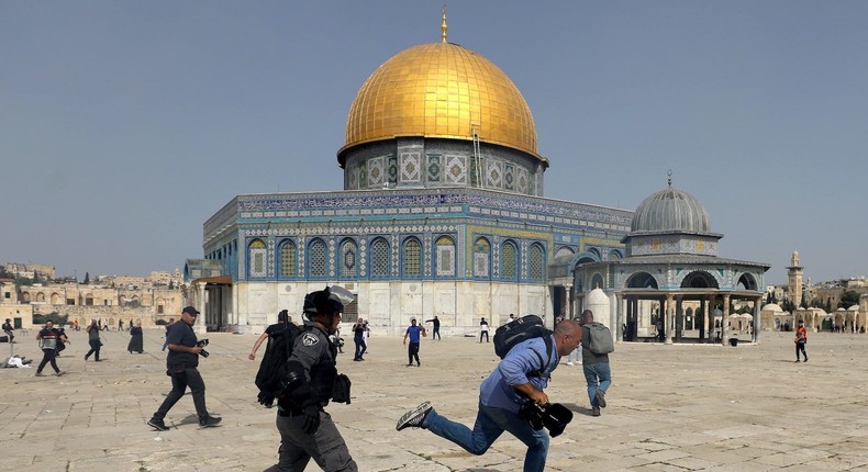 A member of Israeli police runs after a cameraman during clashes with Palestinians at the compound that houses Al-Aqsa Mosque, known to Muslims as Noble Sanctuary and to Jews as Temple Mount, in Jerusalem's Old City, May 10, 2021.
