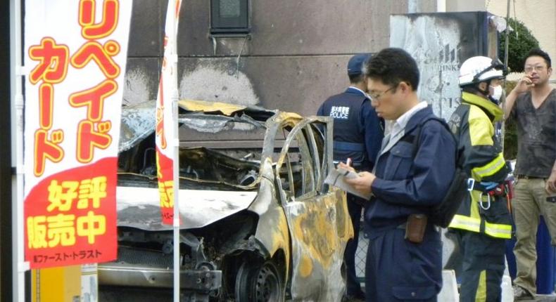 Policemen and firefighters investigate a parking lot after an explosion in Utsunomiya killed one person and at least two injured on October 23, 2016