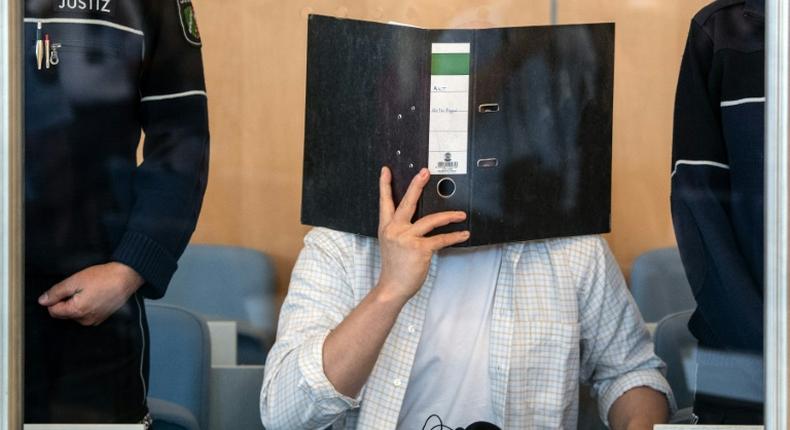 Defendant Sief Allah H. holds a folder in front of his face at the start of his trial on June 7, 2019 at a court in Duesseldorf, western Germany