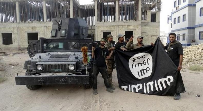 Iraqi security forces hold an Islamist State flag which they pulled down at the University of Anbar, in Anbar province July 26, 2015. REUTERS/Stringer