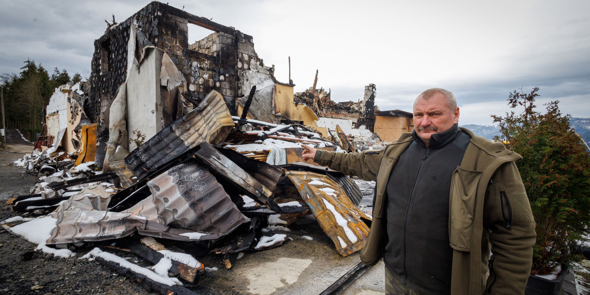 Zbigniew Kamiński (56 l.) na tle spalonego domu w Wiśle. 