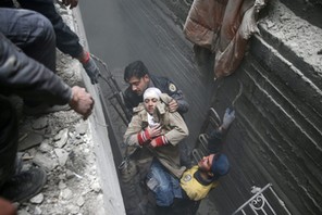 Syria Civil Defence members help an unconscious woman from a shelter in the besieged town of Douma