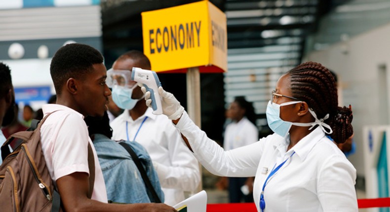 A health worker checks temperature of traveller as part of Coronavirus screening procedure at the Kotoka International Airport