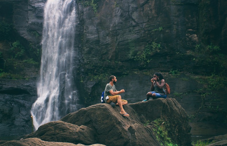 A man and woman near waterfall. Photo by Nandhu Kumar from Pexels.