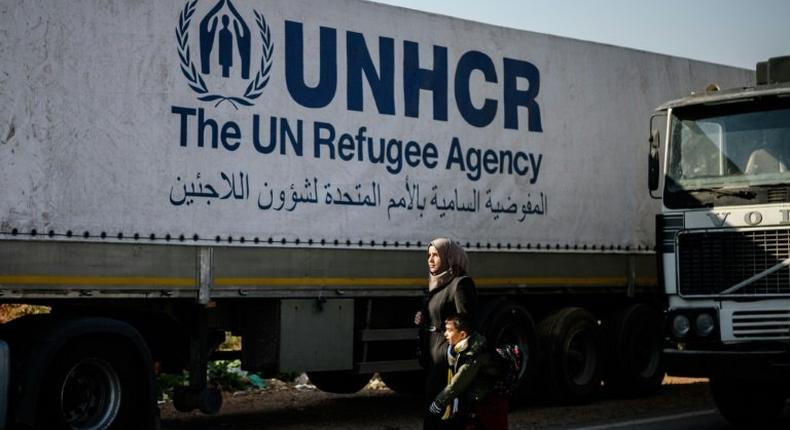 A Syrian woman with her child walks near a Syrian-bound truck loaded with humanitarian aids at the UN transhipment hub at Cilvegozu in Reyhanli near the Turkish-Syrian border in Hatay on November 28, 2016