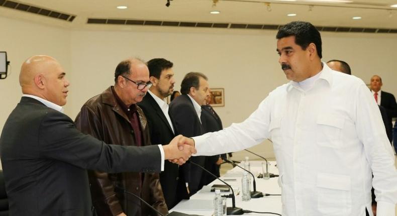 Venezuela's President Nicolas Maduro (right) shakes hands with opposition spokesman Jesus Torrealba at Vatican-backed talks aimed at settling a deepening political crisis in Caracas on October 30, 2016