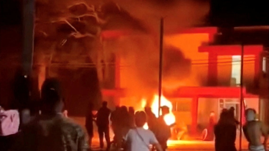 Protivládni demonštranti pozorujú požiar v kancelárii komunistickej strany v Morone, REUTERS