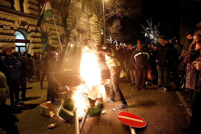Demonstrators add to the stack of burning bins during a protest against the new labour law in front 