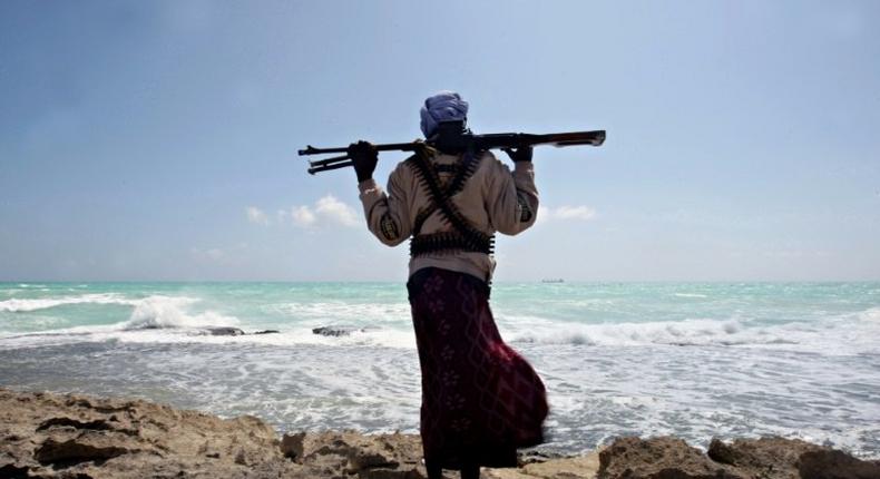 An armed Somali pirate walks along the coastline near Hobyo in 2010