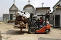 Grave cleaners transport discarded coffins and corpses wrapped in plastic bags on forklift during exhumation works at General Cemetery in Guatemala City