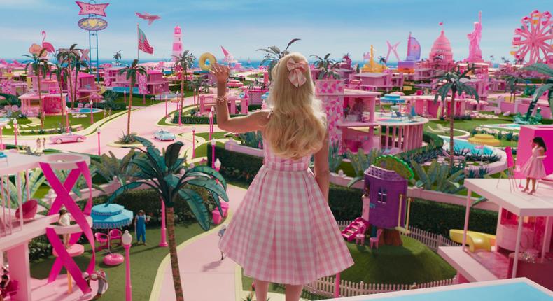 Margot Robbie's Barbie waving to Barbie Land citizens in Barbie.Warner Bros. Pictures