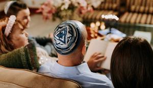 A Jewish family gathered round reading together [Image Credit: RDNE]