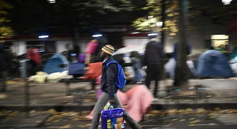 Migrants collect their belongings on the Avenue de Flandre during the evacuation of a makeshift camp in Paris on November 4, 2016