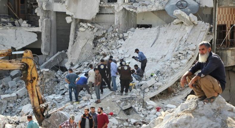 Volunteers search for victims amid the rubble of destroyed buildings on October 24, 2016, following air strikes in the rebel-held town of Kafar Takharim, in Idlib province