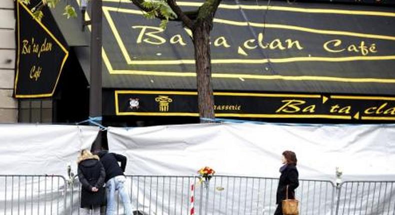 People look through the screened-off facade of the Bataclan Cafe adjoining the concert hall, one of the sites of the deadly attacks in Paris, November 21, 2015.