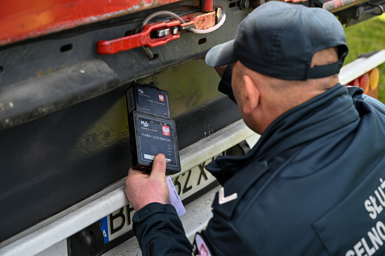 Celnik zakłada elektroniczną plombę na ciężarówce z ukraińskim zbożem, oczekującej na wyjazd z polsko-ukraińskiego przejścia granicznego w Medyce