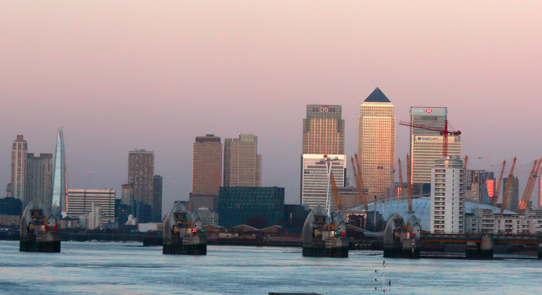 A tug pulls a container barge down the River Thames in front of London's financial district of Canary Wharf in the early morning January 24, 2015.