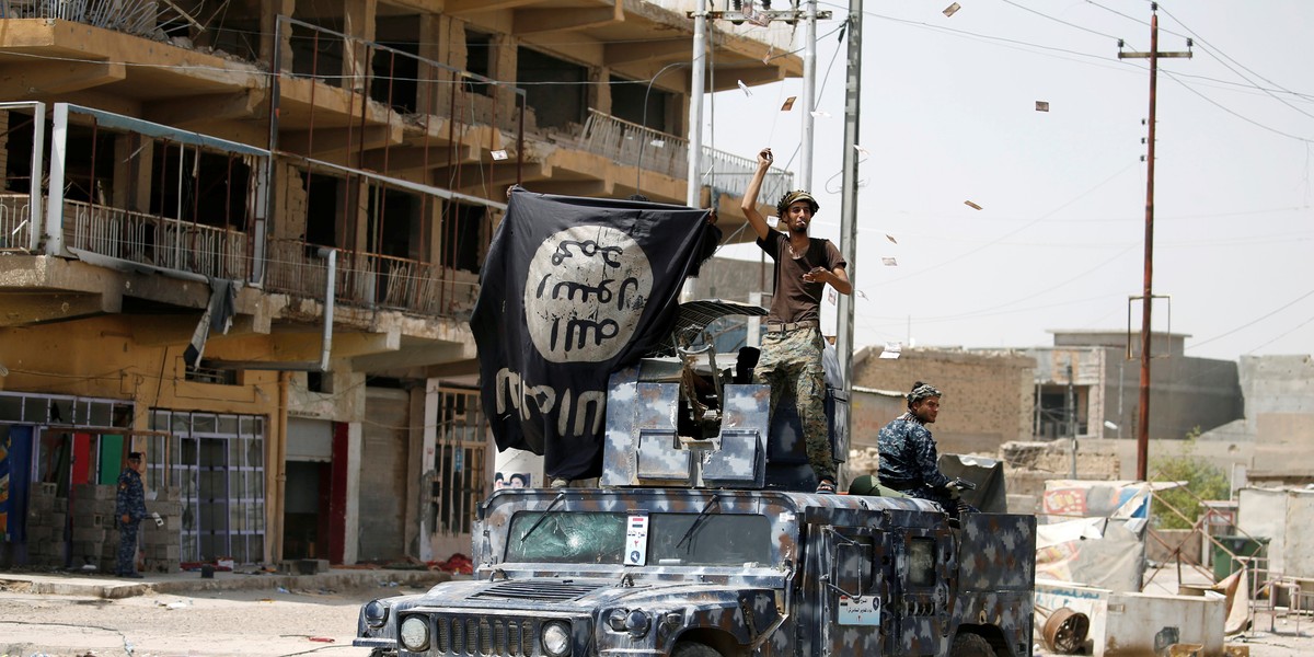 Members of Iraqi government forces celebrate on a street in Fallujah after government forces recaptured the city from ISIS militants on June 27.