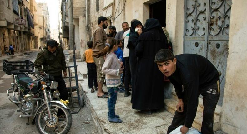 Syrian families receive aid packages by Al-Sham Humanitarian Foundation in a rebel-held neighbourhood of Aleppo on November 15, 2016