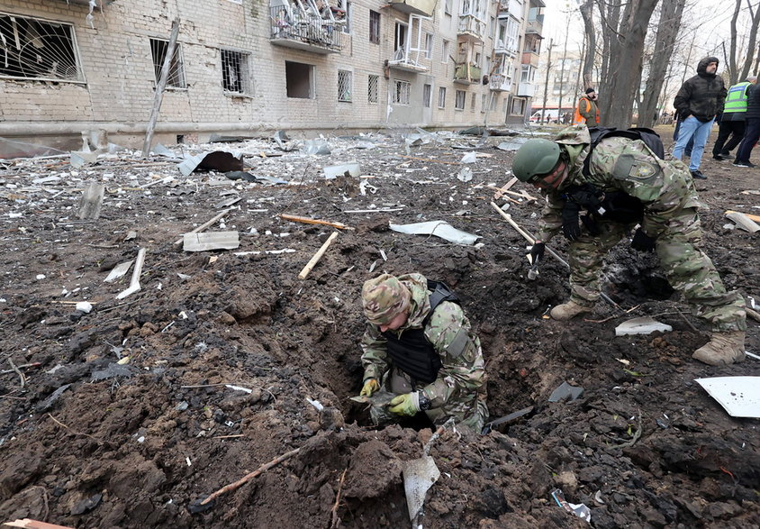 Żołnierz zbiera fragmenty rosyjskiej bomby sterowanej wykorzystanej do ataku na Charków, 27 marca 2024 r.