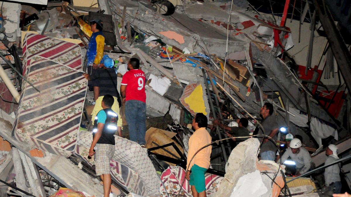 People stand on the debris of a building after an earthquake struck off the Pacific coast in Manta