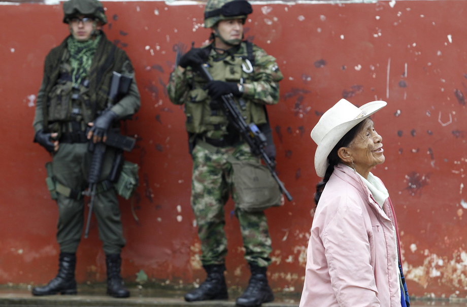 Soldiers stand guard as a woman walks past during a congressional election in Toribio in Colombia's Cauca province, March 9, 2014.