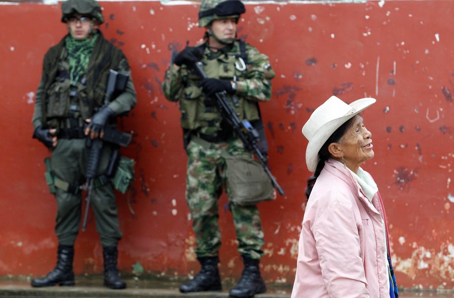 Soldiers stand guard as a woman walks past during a congressional election in Toribio in Colombia's Cauca province, March 9, 2014.