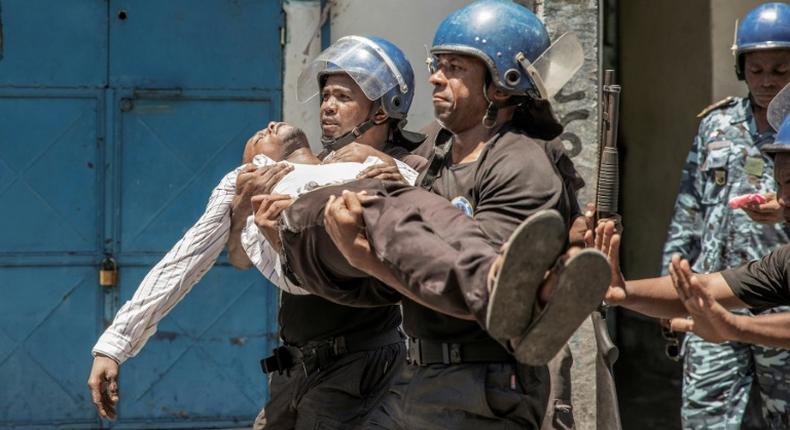 Police take away a plainclothes policeman injured in Monday's clashes